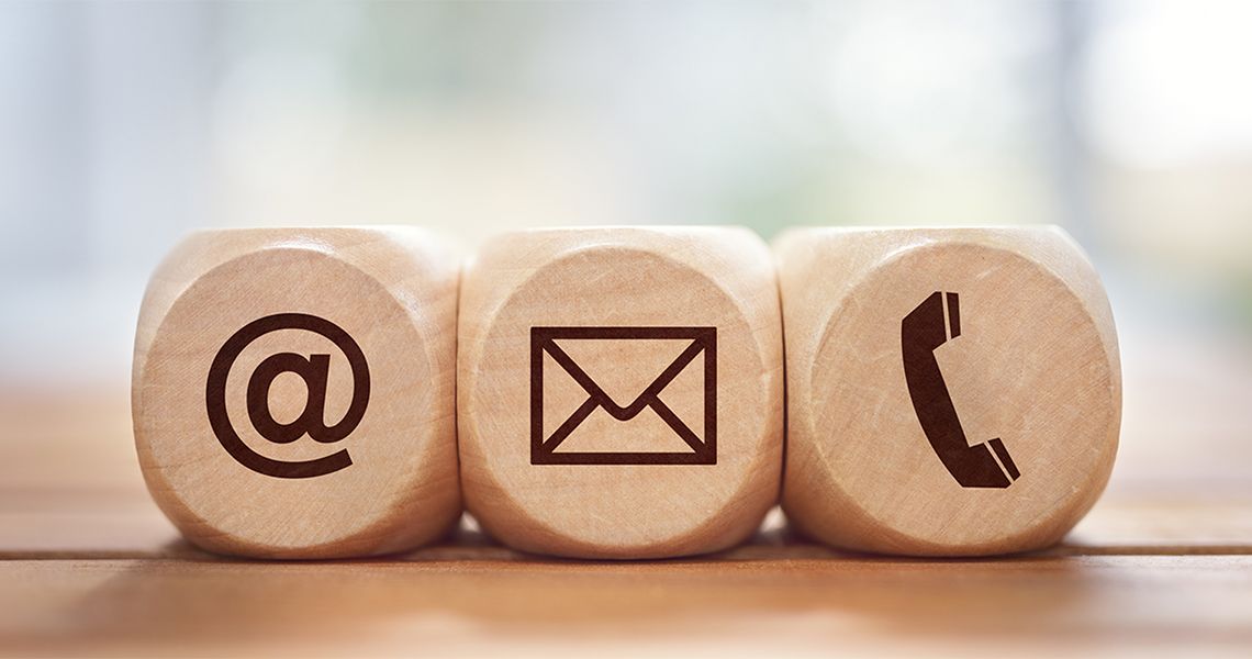 Wooden dice with an @ symbol, envelope symbol, and telephone symbol