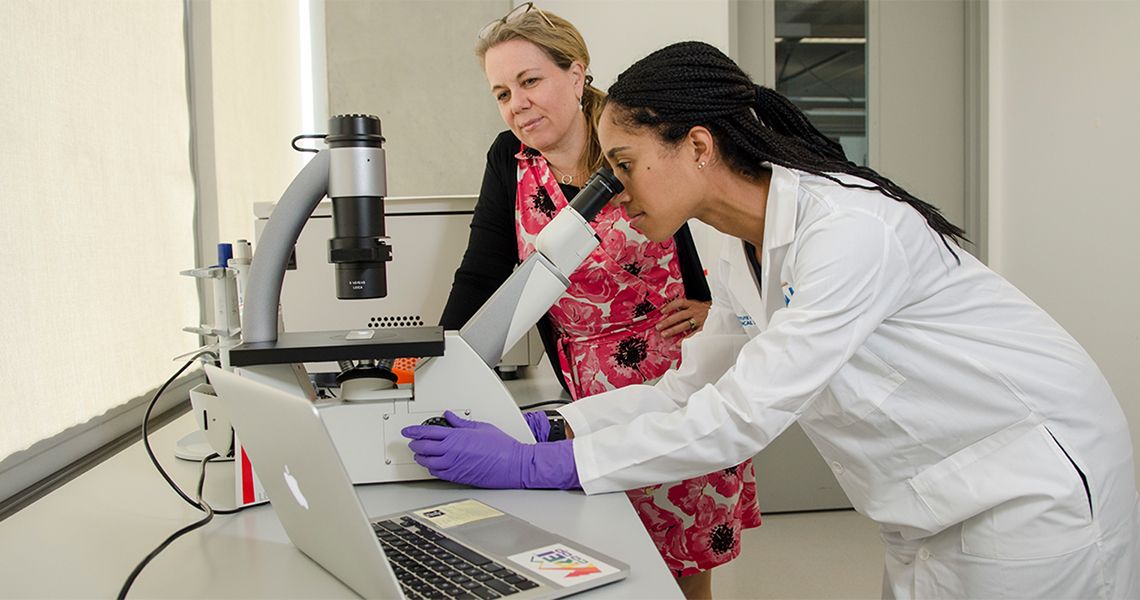 Researcher looking into a microscope