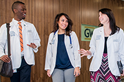 Students in white coats walking down a hall 