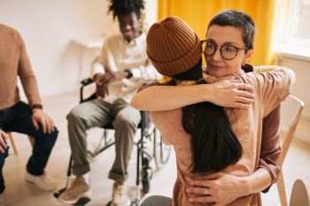 Two women in support group hugging