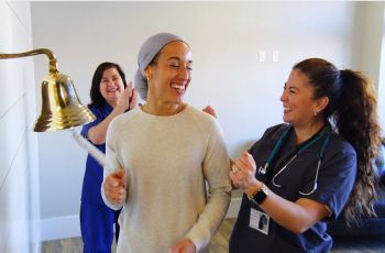 Happy cancer patient ringing the bell after successful treatment